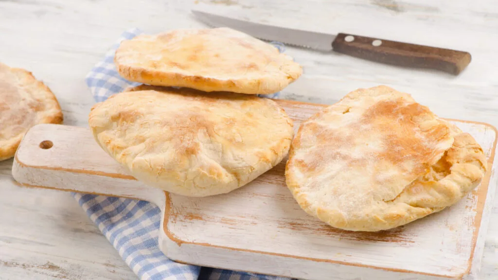 Loaves of pita bread on a wooden cutting board