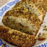 A loaf of pistachio bread sliced into slices on a plate