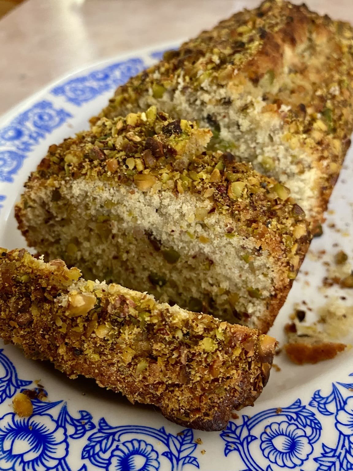 A loaf of pistachio bread sliced into slices on a plate