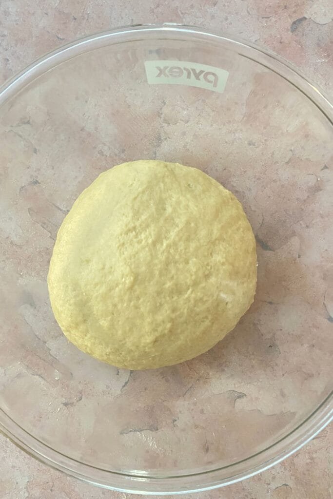 A ball of dough on large bowl after kneading