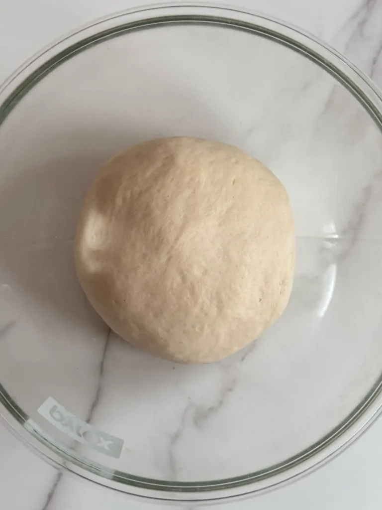 Hoagie rolls dough in glass mixing bowl after kneading process