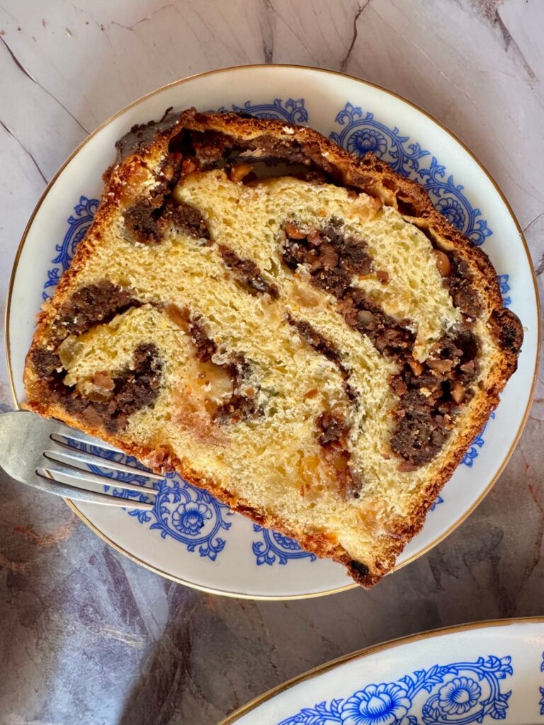 An overhead shot of a single thick slice of Cozonac served on a white vintage plate.