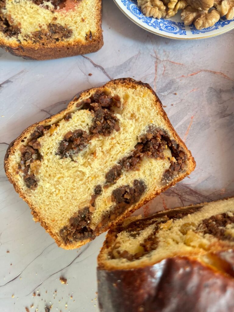 A close-up, overhead view of a thick slice of baked Cozonac bread.