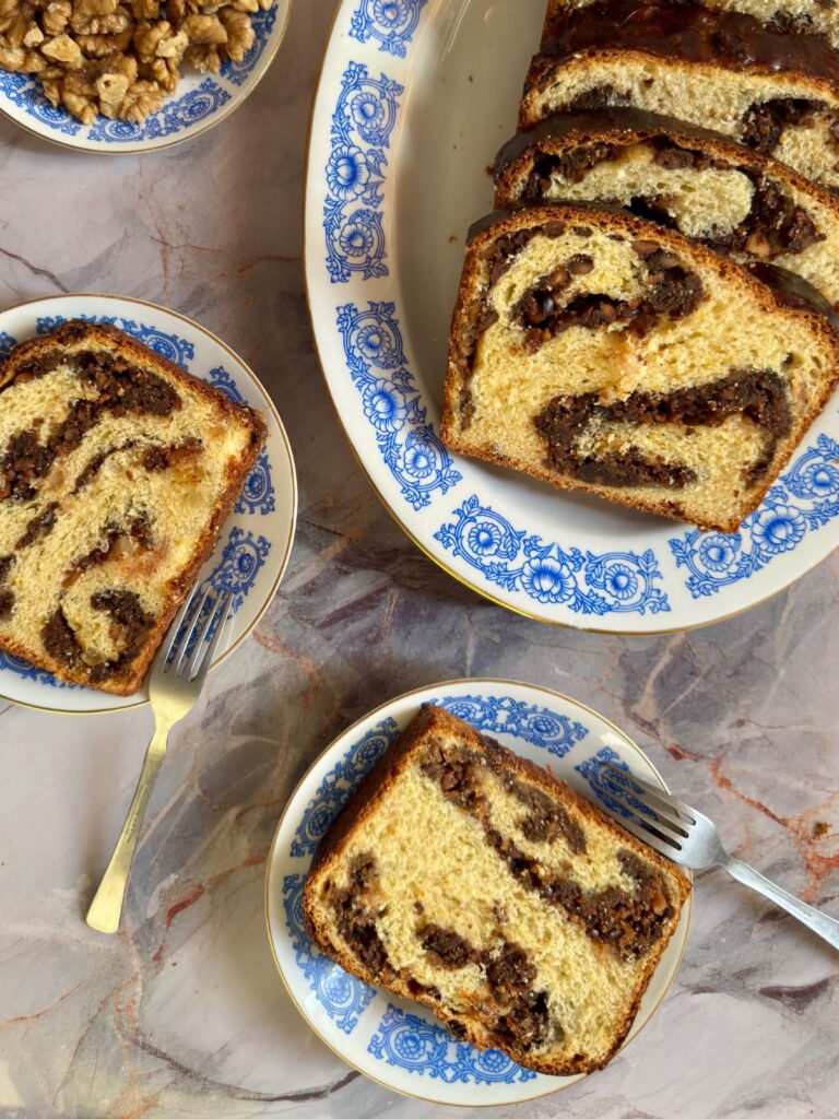 An overhead shot showing thick slices of Cozonac bread resting on a grey marbled countertop.