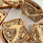 Slices of Povitica walnut swirl bread with powdered sugar on a white plate.
