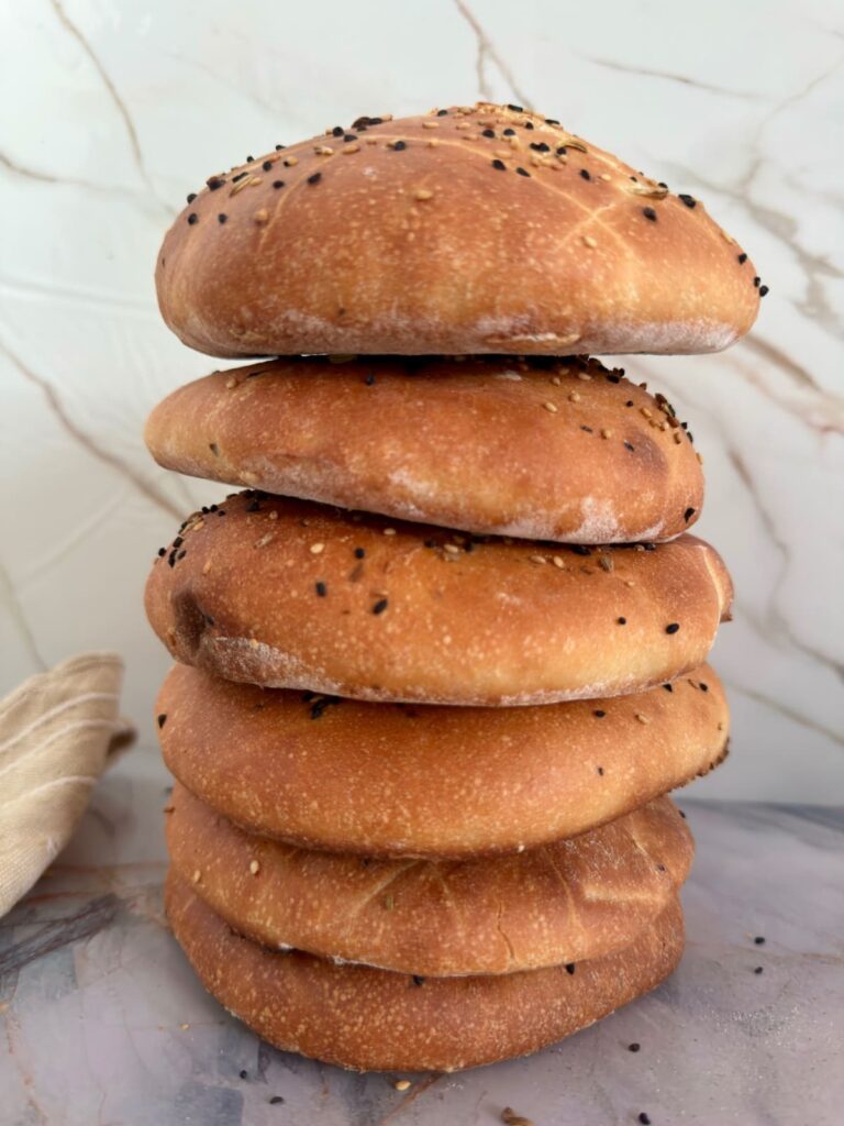 A stack of five golden brown Lepinja breads piled vertically