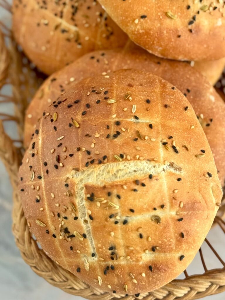 A top-down, close-up view of several Lepinja flatbread resting in a bread basket.