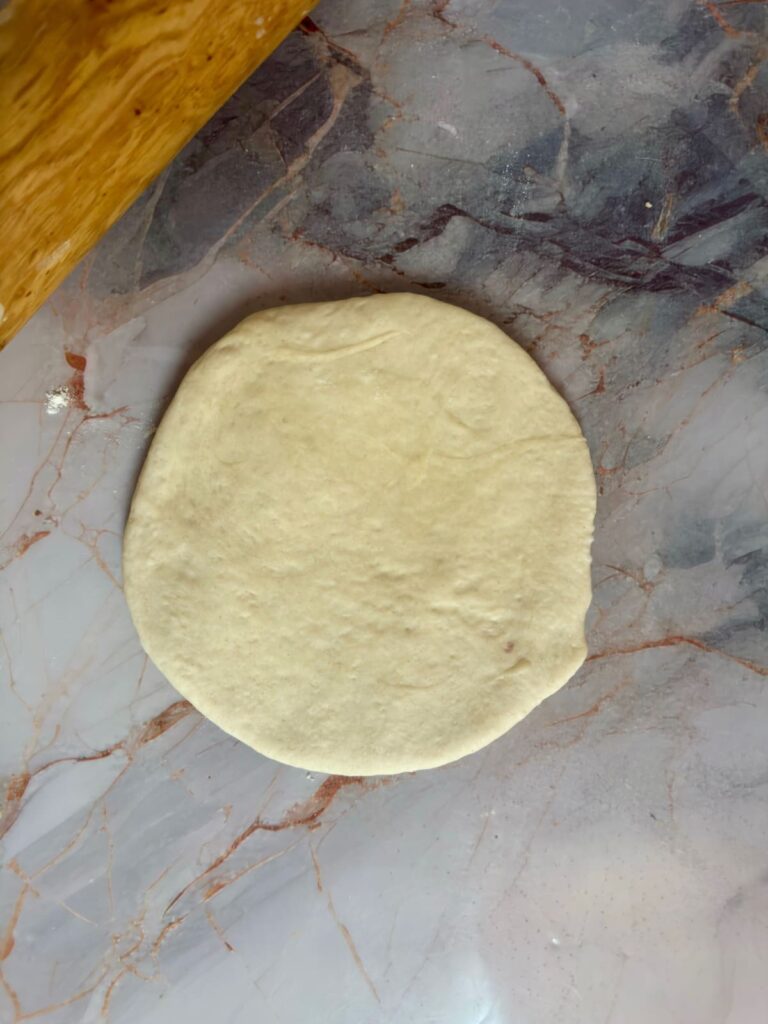 A smooth, circular piece of flattened lepinja dough.