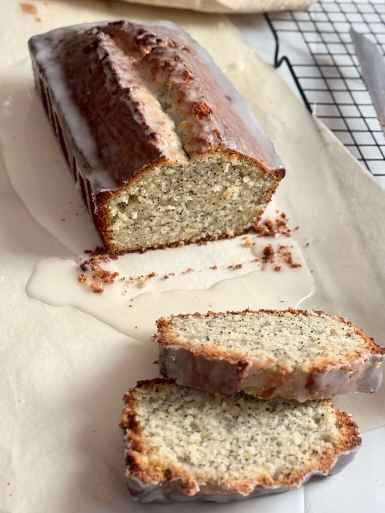 A glazed lemon poppy seed loaf on parchment paper.