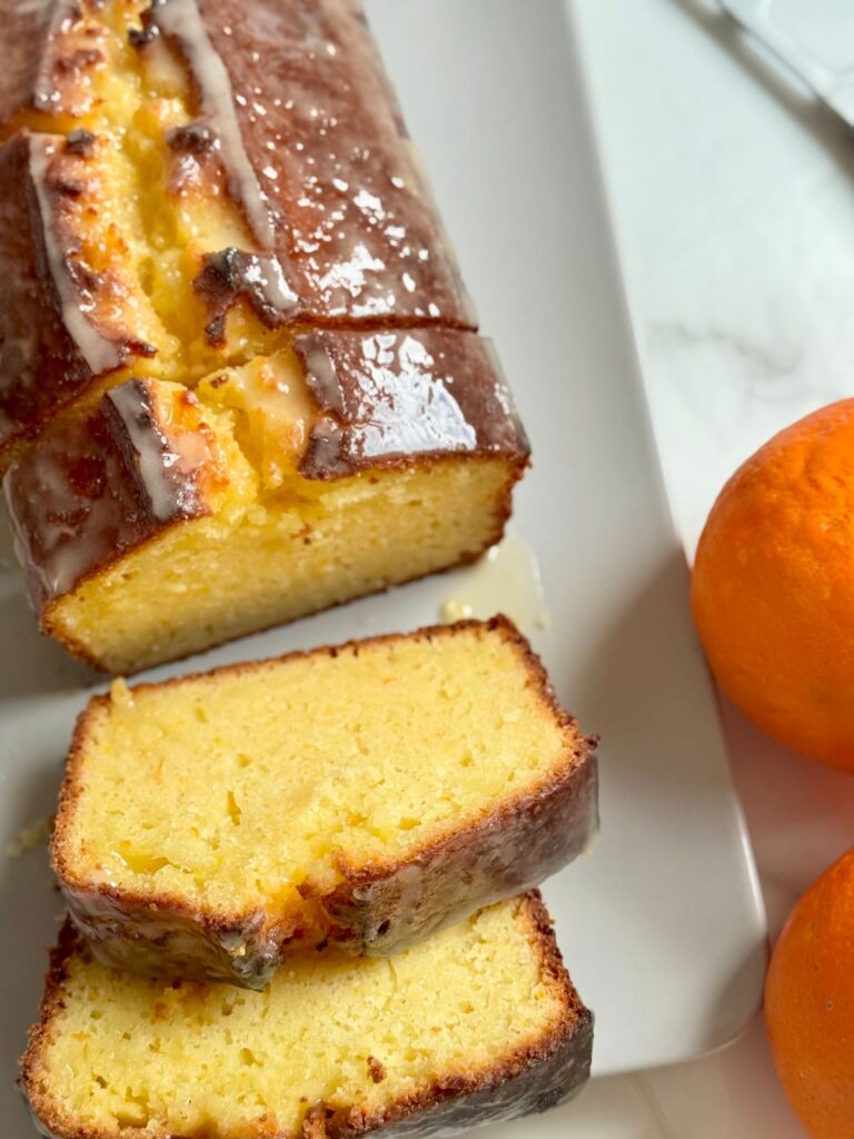 A top-down view of a sliced orange bread loaf on a white platter.