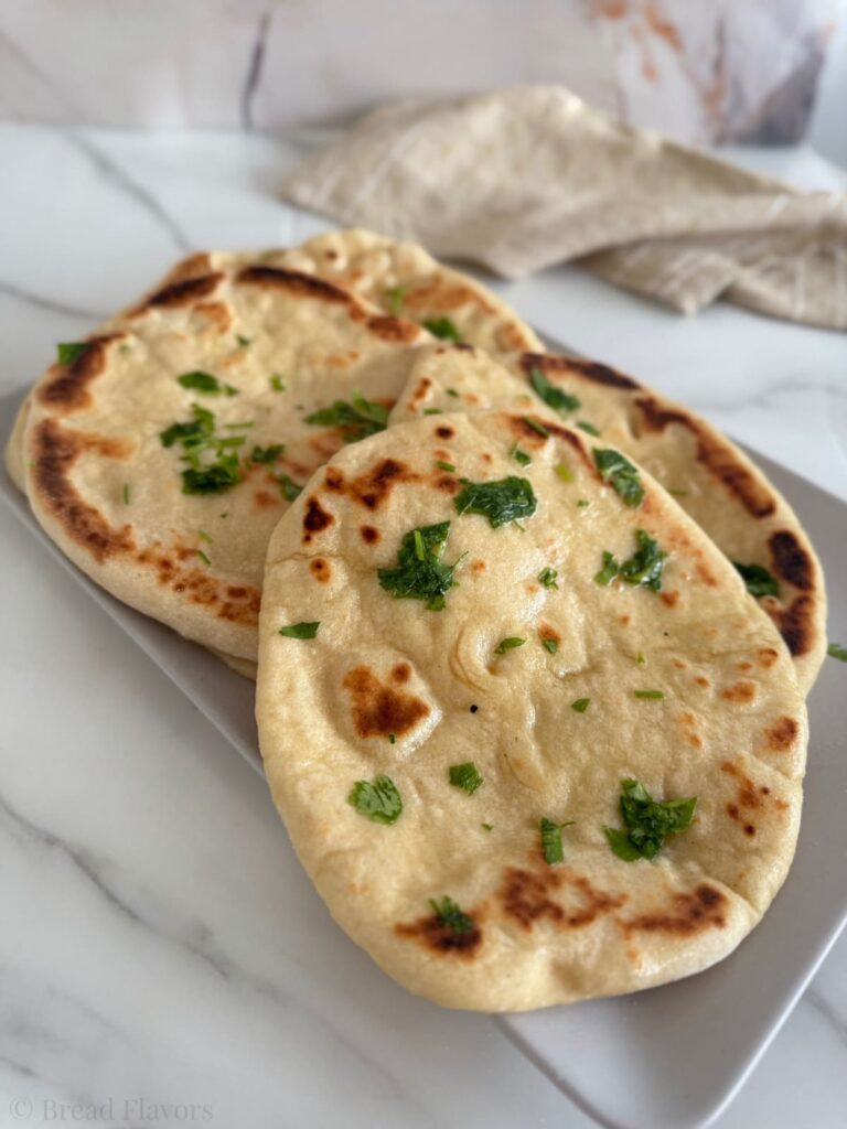 pieces of 2 ingredient naan bread arranged on a white rectangular platter.