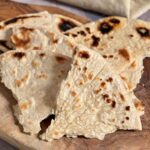 A close-up view of stacked unleavened bread on a wooden board.
