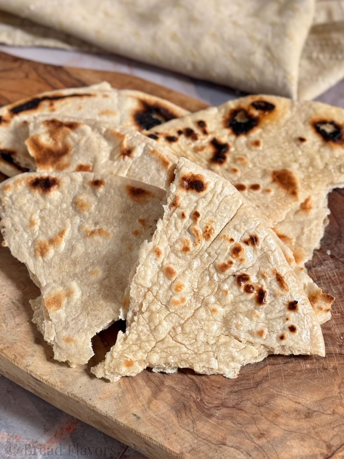 A close-up view of stacked unleavened bread on a wooden board.