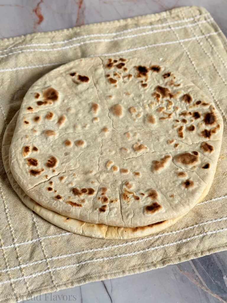 Two perfectly round pieces of unleavened bread are presented on a napkin.