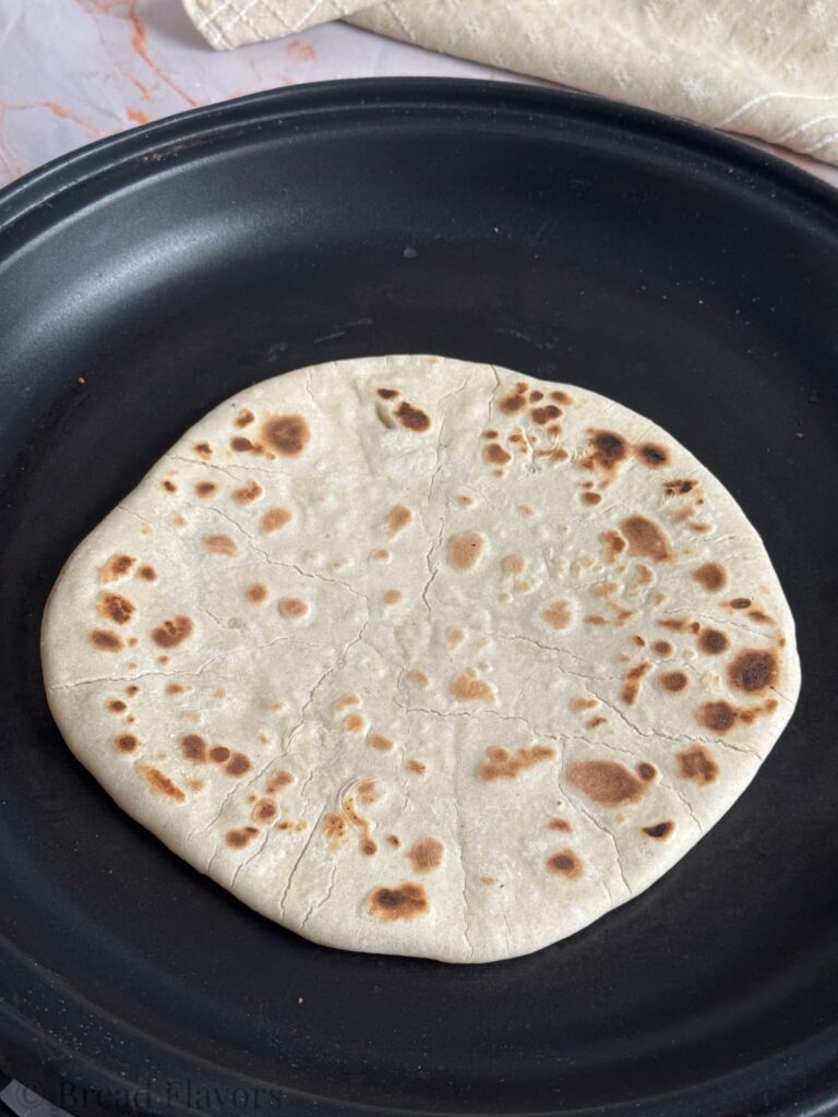 A golden-brown piece of unleavened bread in a skillet.