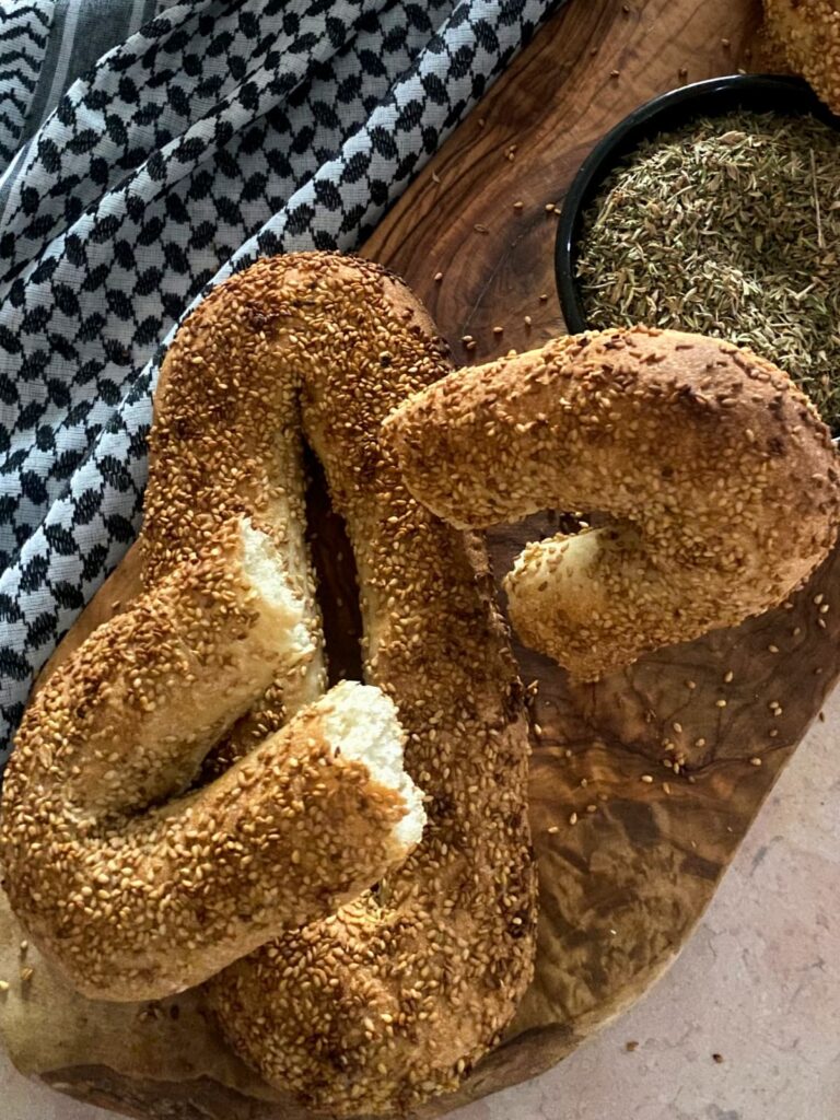 A close-up of a broken Jerusalem bagel showing its soft white interior, resting on a wooden board.