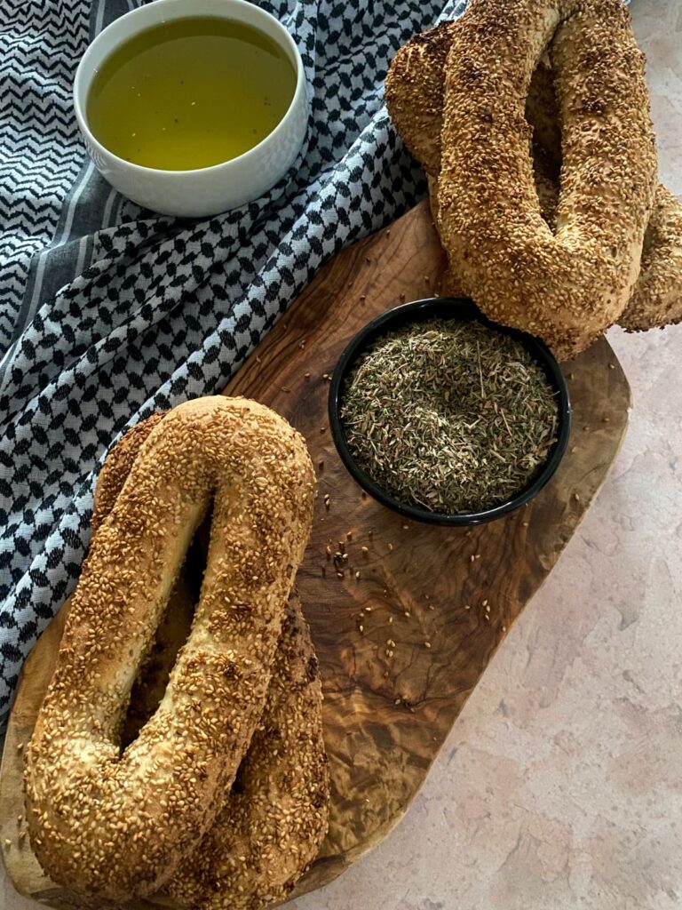 A top-down view of Jerusalem bagels, olive oil, and za'atar arranged on a wooden board.