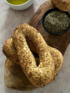 A close-up, angled shot of two Jerusalem bagels on a wooden serving board.