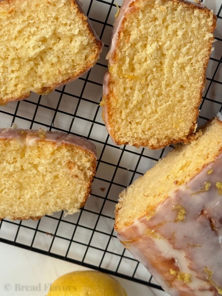 Several thick slices of lemon bread scattered on a black wire rack.