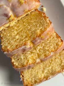 An angled, close-up shot of three slices of lemon loaf on grey platter.
